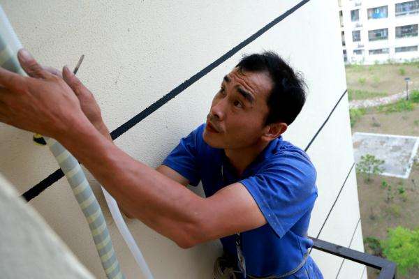 空调安装工小波正在室外高空作业